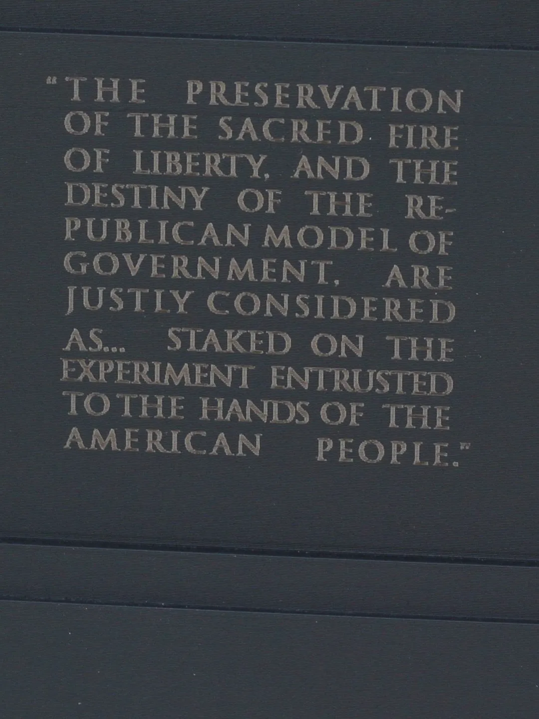 The statue's black base, engraved with Washington's words