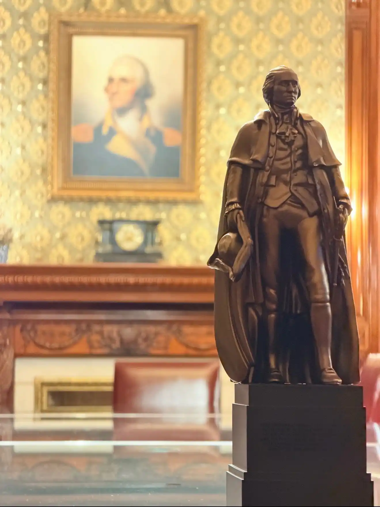 The George Washington statue on a mantel in the White House, beneath a portrait of Washington